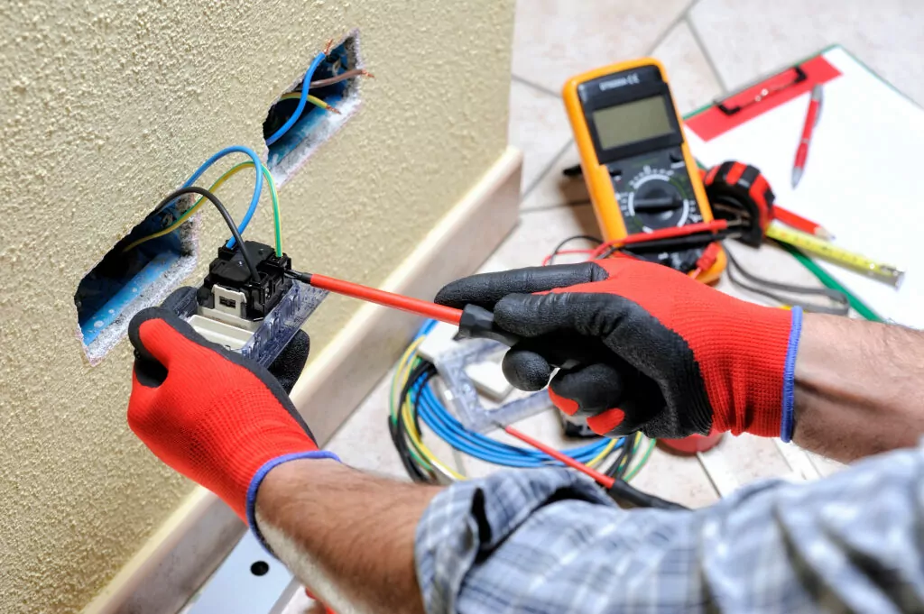 Eletricista com equipamento de segurança a trabalhar numa tomada