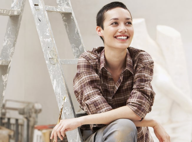 Pessoa sentada numa escada depois de realizar uma tarefa de pintura
